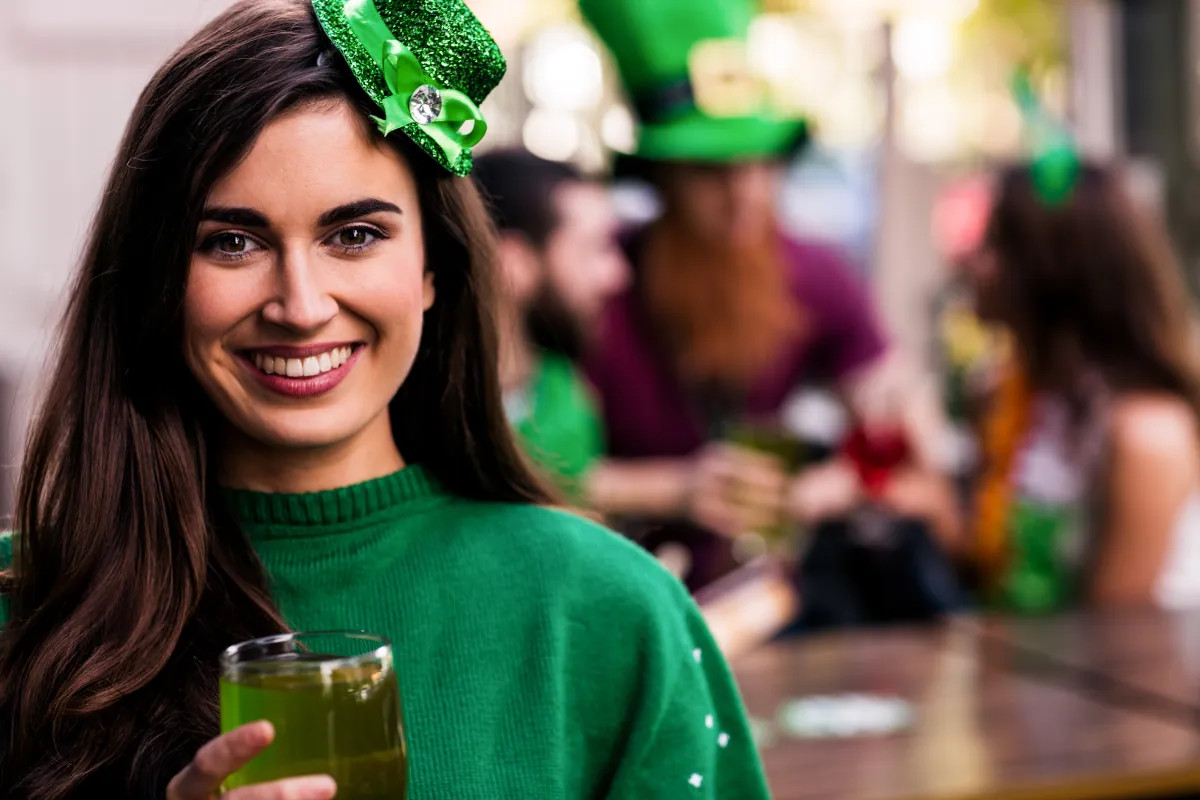 Woman in green sweater and hat celebrating St. Patrick’s Day